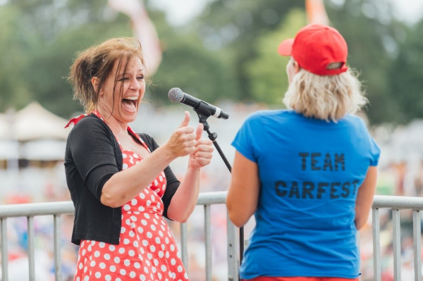 A photo of Lotte Mikkelsen laughing and giving two thumbs up to a women facing away from the camera wearing a blue t-shirt that says Team Carfest on the back.
